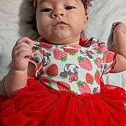 Leilani is registered to the contest to win money with this photo: baby, infant, child, headband, strawberry_pattern, red_tutu, white_quilt, cute, portrait, lying_down, clothing, toddler, apparel, person, face, hand, expression, fashion, colorful, soft_texture