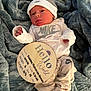 newborn, baby, nike, hat, blanket, wooden_sign, birth_announcement, clothing, infant, cute, sleepy, portrait, indoor, soft_texture, lying_down, person, small_hands, baby_clothes, headwear, resting