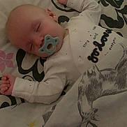 Lennie is registered to the contest to win money with this photo: baby, sleeping, pacifier, blanket, bedspread, deer, floral_pattern, infant, cozy, cute, child, resting, indoors, soft_lighting, wearing_clothes, peaceful, pajamas, hands_up, face, head