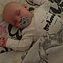 baby, sleeping, pacifier, blanket, bedspread, deer, floral_pattern, infant, cozy, cute, child, resting, indoors, soft_lighting, wearing_clothes, peaceful, pajamas, hands_up, face, head