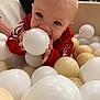 toddler, child, ball_pit, white_ball, cream_ball, red_jacket, indoor, play, baby, curious, face, hands, people, background, smile, fun, toy, young_child, closeup, casual