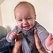 Axl is registered to the contest to win money with this photo: baby, child, smiling, happy, onesie, hands, indoor, person, face, infant, playful, young, cute, portrait, human, expression, fingers, lifting, clothing, room