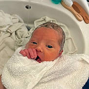Vincent is registered to the contest to win money with this photo: baby, bath, bathroom_sink, brush, comb, cute, face, fingers, hand, indoor, infant, mouth, newborn, pacifier, person, skin, towel, wet_hair, white, wrapped