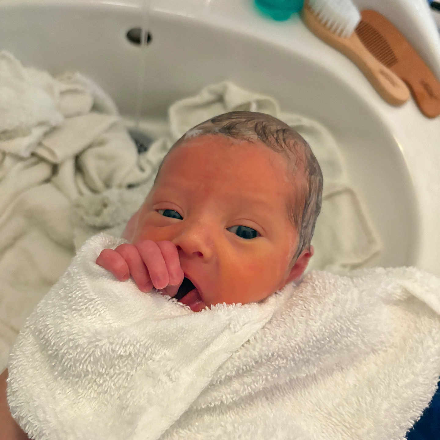 Vincent is registered to the contest to win money with this photo: baby, bath, bathroom_sink, brush, comb, cute, face, fingers, hand, indoor, infant, mouth, newborn, pacifier, person, skin, towel, wet_hair, white, wrapped
