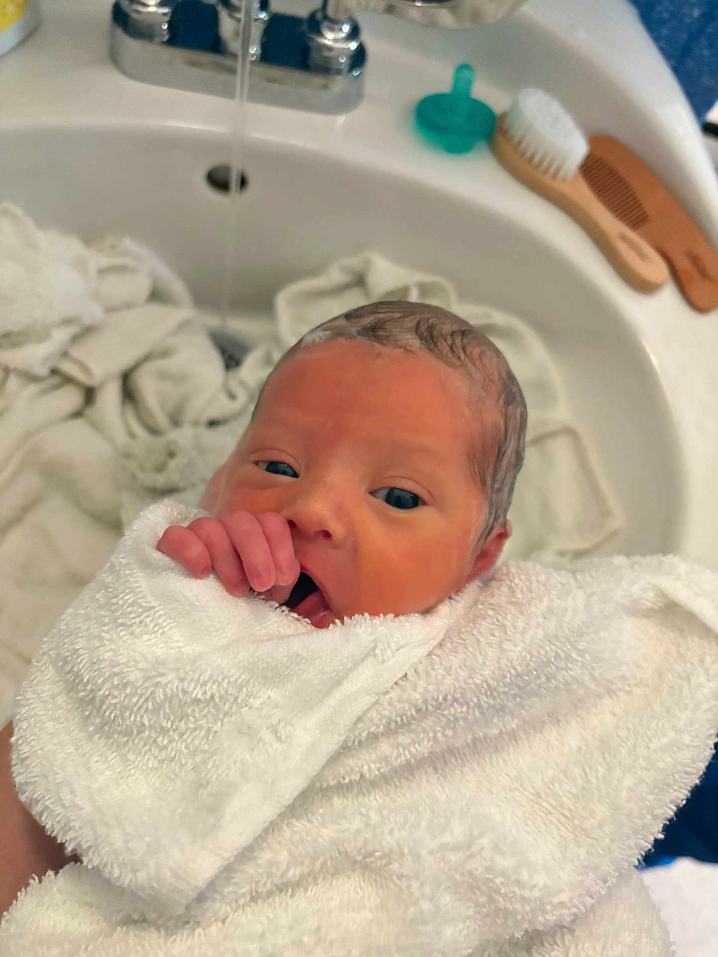 Vincent is registered to the contest to win money with this photo: newborn, baby, towel, bathroom_sink, pacifier, brush, comb, hand, face, wet_hair, infant, wrapped, cute, skin, mouth, fingers, person, indoor, bath, white