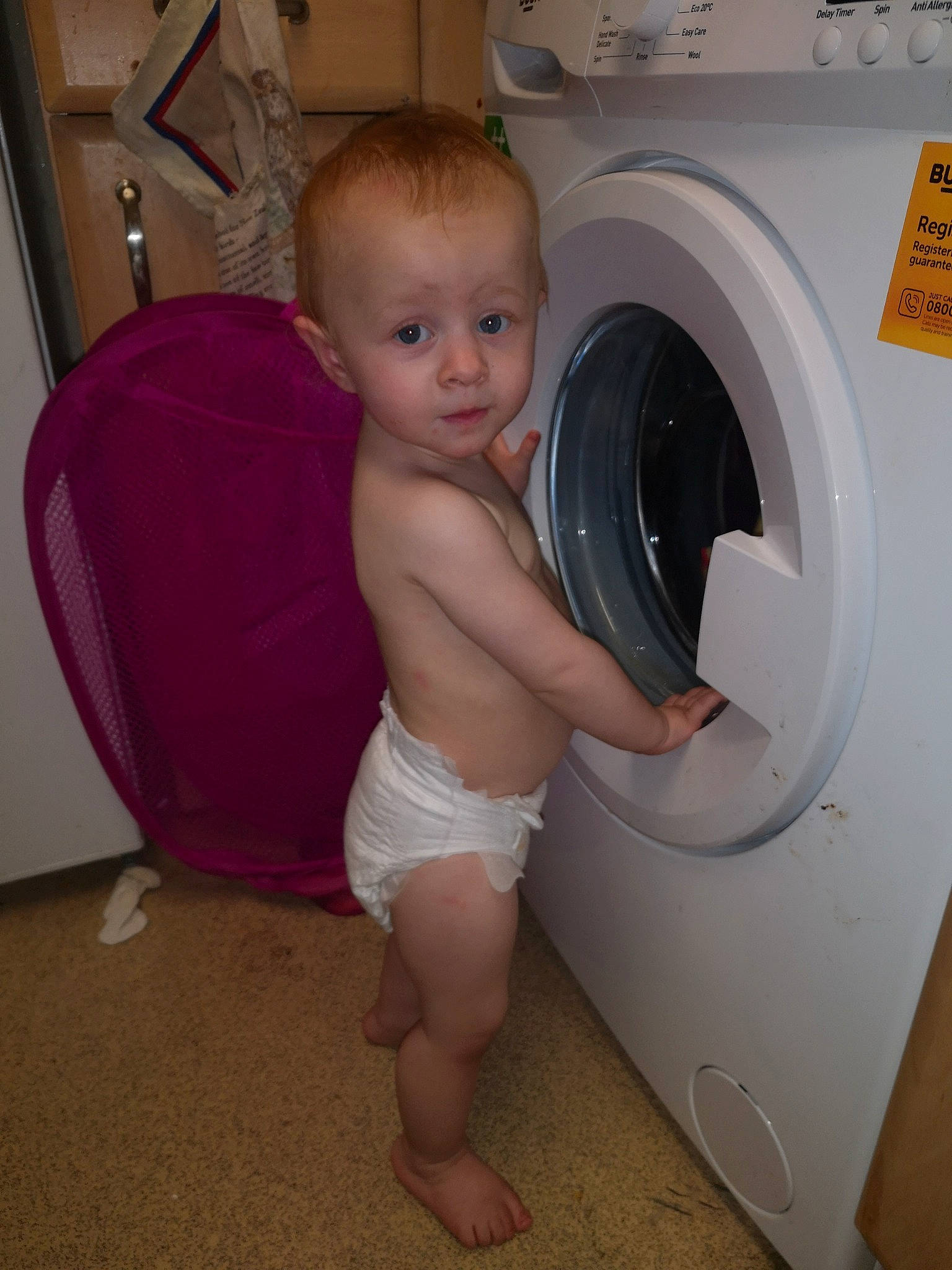Charmaine is registered to the contest to win money with this photo: baby_toddler_clothing, barefoot, child, clothes_dryer, elbow, floor, flooring, foot, home_appliance, human_leg, laundry, laundry_room, major_appliance, organ, person, shoulder, thumb, toddler, toe, trunk