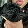dog, pug, black_dog, close_up, face, person, hand, lips, kiss, pet, cute, expression, indoor, portrait, animal, young_adult, holding, nail_polish, ring, long_hair