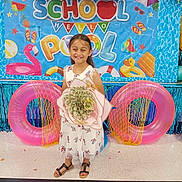 Emma joined the competition — help win amazing prizes! child, girl, smiling, dress, sandals, bouquet, balloons, inflatable_ring, backdrop, party, celebration, floor, decoration, summer, pool_theme, happy, indoor, event, colorful, flower