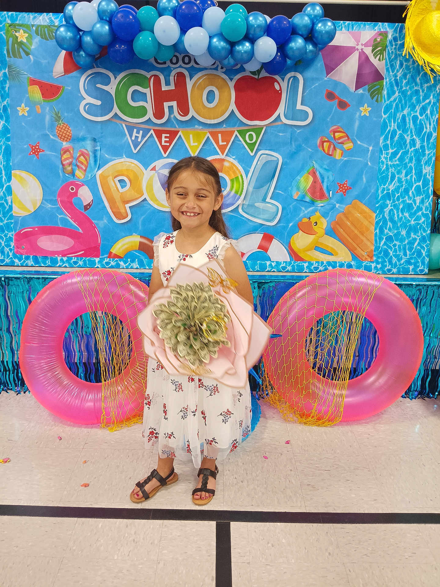 Emma joined the competition — help win amazing prizes! child, girl, smiling, dress, sandals, bouquet, balloons, inflatable_ring, backdrop, party, celebration, floor, decoration, summer, pool_theme, happy, indoor, event, colorful, flower