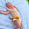 baby, infant, blanket, unicorn_pattern, outdoor, grass, onesie, peach_color, toy, rattle, smile, happy, relaxed, child, cute, lying_down, pastel_colors, playtime, soft_texture, nature