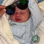Oakley-Jay is registered to the contest to win money with this photo: baby, sleeping, blanket, pajamas, striped_clothing, pacifier, hand, sunglasses, cozy, infant, cute, soft_texture, cute_accessory, wrapped, indoors, newborn, resting, peaceful, person, sleep