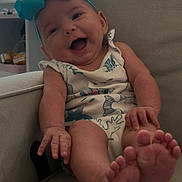 Delilah is registered to the contest to win money with this photo: baby, smiling, headband, bow, onesie, infant, happy, sitting, feet, hand, armchair, indoor, window, child, cute, portrait, furniture, skin, expression, relaxed