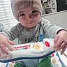 activity_seat, baby, child, close_up, colorful, family_photos, frog_pattern, gray_shirt, hands, hat, home, indoors, infant, knit_hat, playtime, portrait, sitting, smiling, toy, window