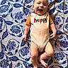baby, child, infant, onesie, happy, smiling, lying_down, blanket, patterned, blue, white, cute, playful, joy, innocence, person, skin, head, arms, legs