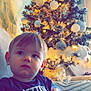 Alessio participe au concours pour gagner de l'argent avec cette photo : child, toddler, boy, pacifier, christmas_tree, ornaments, fairy_lights, holiday, living_room, couch, sitting, portrait, interior, festive, decorations, cozy, gaze, shirt, face, holiday_decor