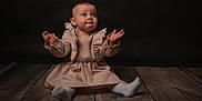 Thalia participe au concours pour gagner de l'argent avec cette photo : baby, child, infant, sitting, dress, beige, wooden_floor, studio, portrait, curious, expression, hands, looking_up, floor, cute, indoor, young_child, soft_lighting, ruffles, sock
