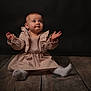 baby, child, infant, sitting, dress, beige, wooden_floor, studio, portrait, curious, expression, hands, looking_up, floor, cute, indoor, young_child, soft_lighting, ruffles, sock