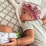 Kora joined the competition — help win amazing prizes! baby, bed, blanket, checkered_clothing, child, chubby_cheeks, curious, cute, hand, indoors, infant, pattern, person, pink_bonnet, pout, side_view, sleepwear, snack_pack, soft_lighting, toddler
