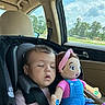 blue_overalls, car_interior, car_seat, child, clouds, daytime, doll, headband, infant, nature_outside, pink_shirt, relaxation, safety_harness, seatbelt, sleeping, sunlight, toddler, toy, trees, window