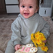 Iris-Anastasia a rejoint le concours — aidez-le/la à gagner de superbes lots ! baby, child, infant, girl, smiling, pigtails, flower_bouquet, dandelions, milestone, plaque, sitting, gray_clothing, hoodie, pants, indoor, carpet, happy, cute, portrait, person