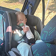 Rémy participe au concours pour gagner de l'argent avec cette photo : baby, car_seat, sleeping, pacifier, bottle, child, car_interior, seatbelt, sunlight, window, travel, infant, clothing, safety, seat, child_safety, rest, peaceful, transportation, young_child