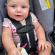 Kaylonni is registered to the contest to win money with this photo: baby, child, car_seat, safety_harness, plush_toy, stuffed_animal, pink_clothing, infant, cute, smiling, hand, foot, seatbelt, warning_label, indoors, person, child_safety, toddler, closeup, seat