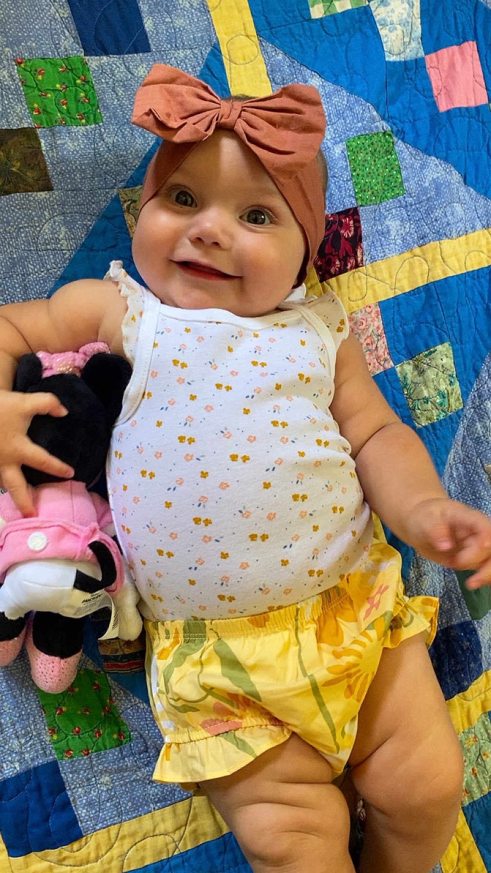 Kaylonni joined the competition — help win amazing prizes! baby, child, smiling, headband, bow, plush_toy, minnie_mouse, quilt, patchwork, colorful, yellow_shorts, white_tank_top, floral_pattern, cute, happy, indoors, person, infant, toddler, clothing