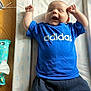 baby, infant, blue_shirt, adidas, smiling, arms_up, changing_pad, wooden_floor, baby_wipes, happy, cute, laying_down, patterned_pad, clothing, child, person, indoor, bright, young, cheerful