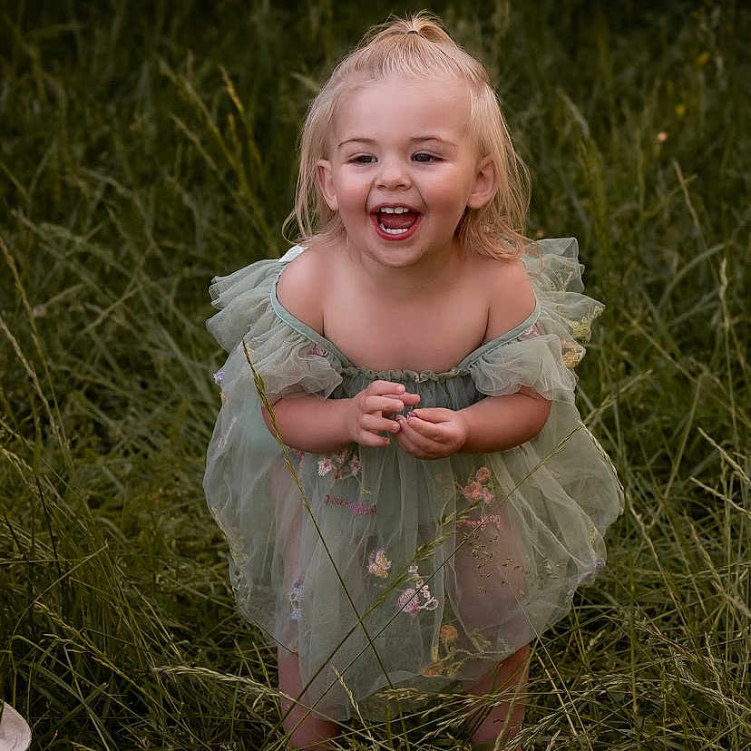 Scarlett joined the competition — help win amazing prizes! barefoot, blonde_hair, child, cute, daylight, flower_embroidery, girl, grass, green_dress, happy, joy, laughing, nature, outdoor, playful, pony_tail, portrait, standing, summer, toddler
