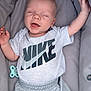 Teddie is registered to the contest to win money with this photo: baby, infant, nike, clothing, pacifier, bassinet, cushion, sleeping, mouth_open, relaxing, child, person, apparel, casual_wear, indoor, cute, soft, comfort, small_person, rest