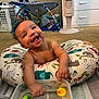 Legend is registered to the contest to win money with this photo: baby, smiling, happy, infant, toy, rubber_duck, water, container, pillow, animal_print, carpet, indoor, fan, baby_gym, plastic_toy, child, playtime, cute, cheerful, room
