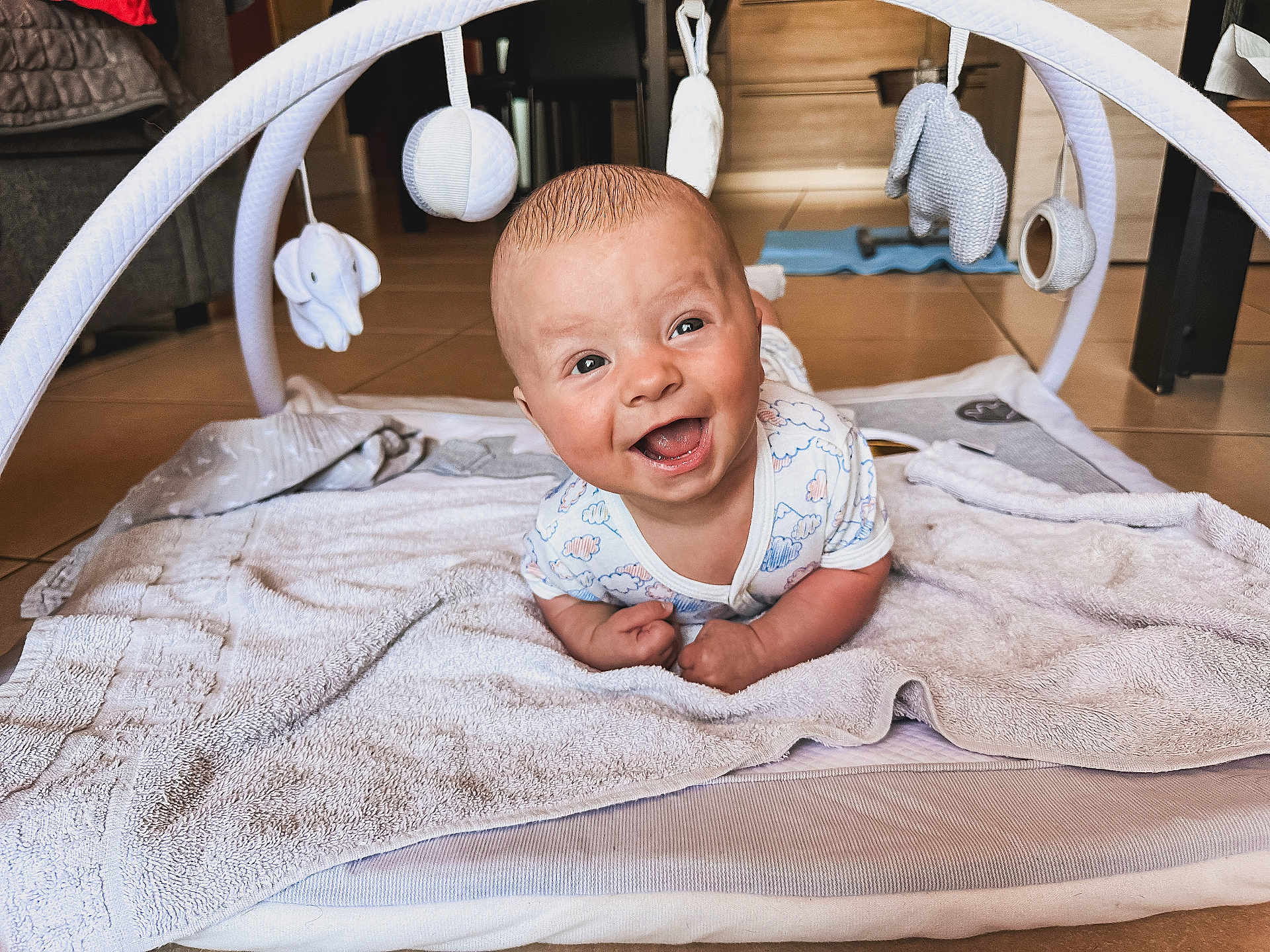 Enzo participe au concours pour gagner de l'argent avec cette photo : baby, smiling, happy, infant, play_mat, baby_gym, toy, indoor, floor, towel, cute, child, person, head, eyes, mouth, skin, clothing, home, playtime