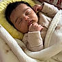baby, sleeping, blanket, pillow, elephant_pattern, soft_texture, infant, cozy, peaceful, child, wrapped, closeup, indoors, cute, warm, resting, peace, face, hand, clothing