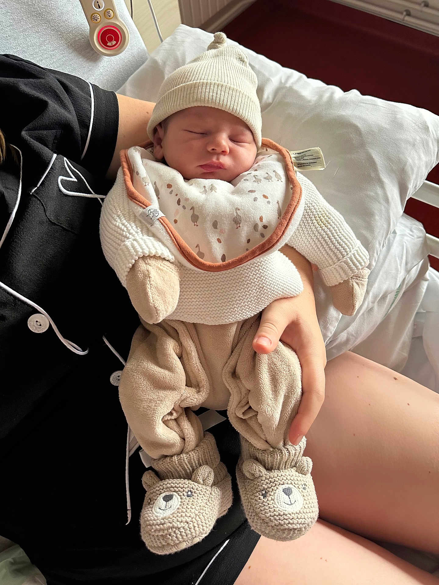 Liam a rejoint le concours — aidez-le/la à gagner de superbes lots ! baby, newborn, sleeping, knit_hat, booties, bear_design, bib, person, hospital_bed, blanket, hand, clothing, pajamas, indoor, bed, resting, cute, warm, infant, cozy