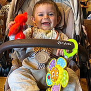 Liam a rejoint le concours — aidez-le/la à gagner de superbes lots ! baby, stroller, toy, smiling, indoor, child, happy, colorful, rattle, clothing, socks, face, seatbelt, person, infant, playful, furniture, people, restaurant, seated
