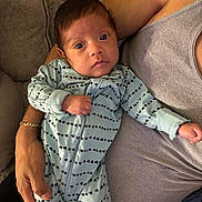 Alexander Torres is registered to the contest to win money with this photo: adult, arm, baby, blue_clothing, casual, closeup, couch, face, gray_clothing, hand, holding, indoor, infant, newborn, onesie, patterned_clothing, person, portrait, relaxing, soft_furniture