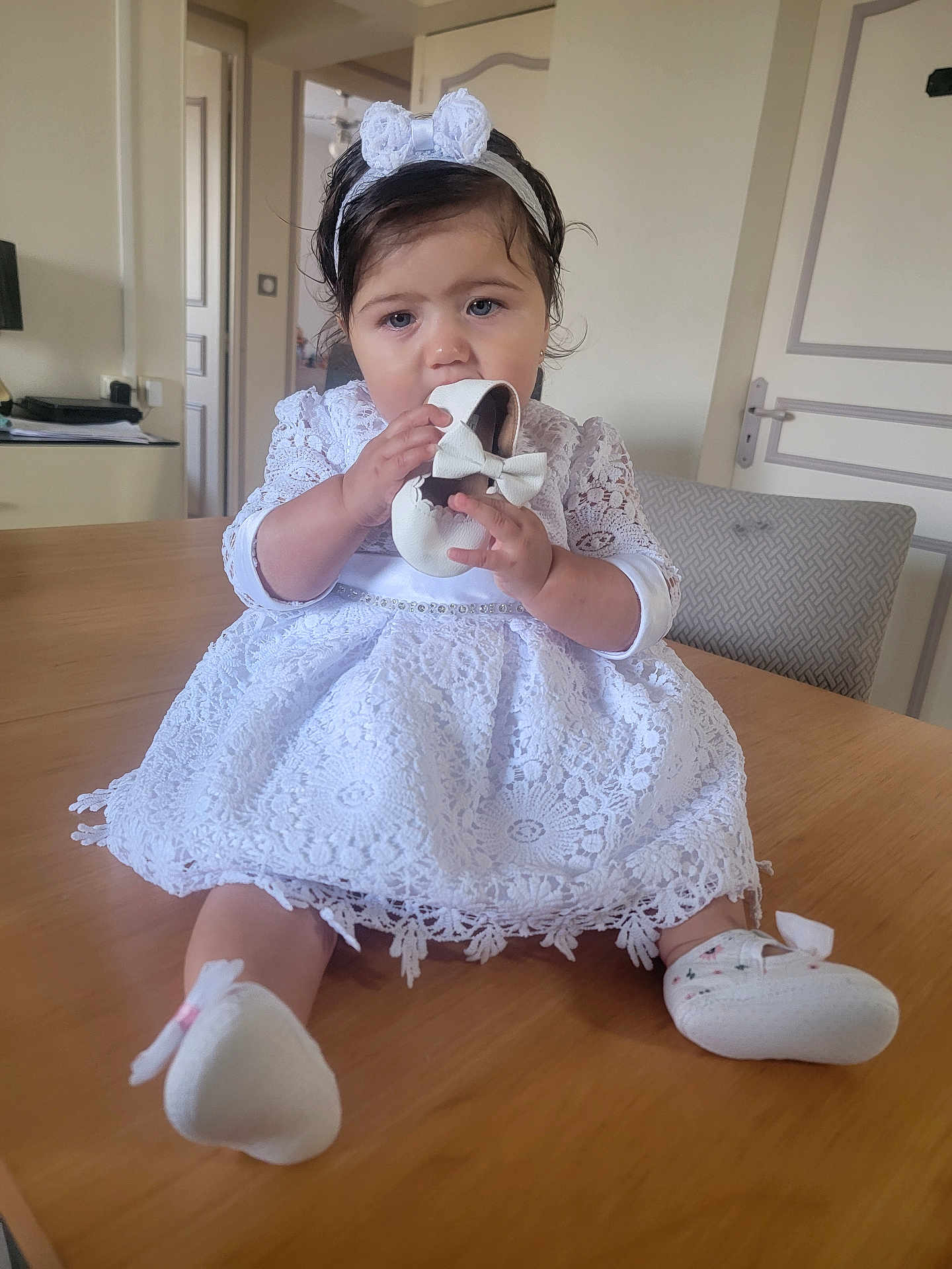Emily participe au concours pour gagner de l'argent avec cette photo : baby, child, white_dress, lace, headband, shoe, table, indoor, curious, sitting, footwear, cute, infant, portrait, person, homedecor, furniture, hand, face, expression
