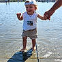 adult_hand, barefoot, building, cap, child, cityscape, hand_holding, happy, outdoor, play, reflection, shadow, shirt, shorts, sky, splashing, summer, sunny, toddler, water