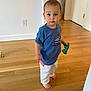 Tyler is registered to the contest to win money with this photo: barefoot, blue_shirt, casual_clothing, child, curious, door, expression, floor, holding_object, home, indoor, person, standing, sunglasses, toddler, toy, wall, white_pants, wooden_floor, young_child