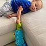 Tyler is registered to the contest to win money with this photo: beige_couch, blue_shirt, carpet, casual_clothing, child, couch, curious, face, floor, furniture, hand, home, indoor, leisure, play, relaxing, toddler, toy, vacuum_cleaner, young_child