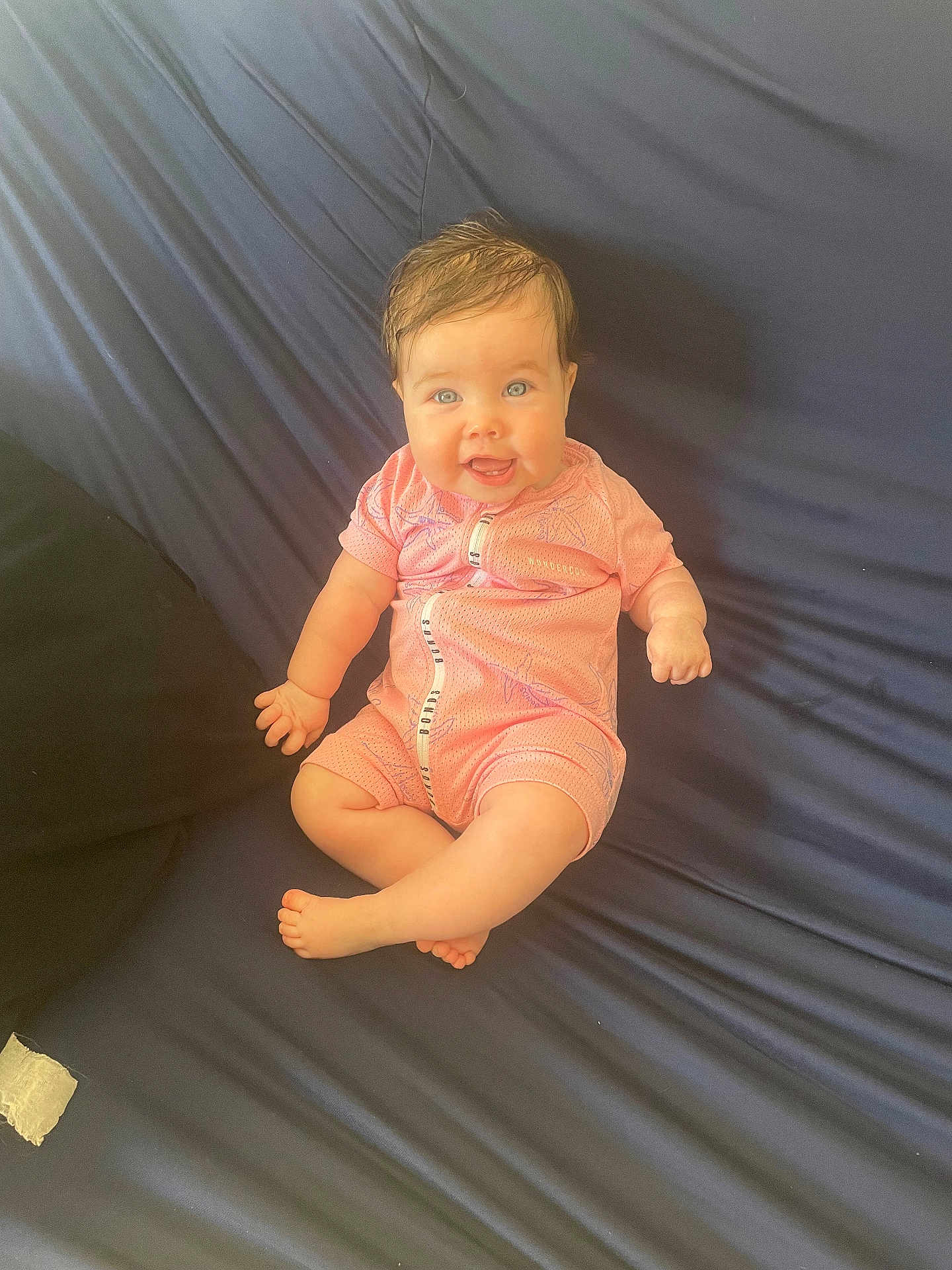 Isla joined the competition — help win amazing prizes! baby, blue_eyes, pink_onesie, smiling, wet_hair, couch, infant, happy, sitting, child, young, indoor, clothing, face, person, cute, skin, furniture, portrait, young_child
