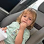 toddler, child, car_seat, car_interior, blonde_hair, tshirt, woody_character, cup, seatbelt, portrait, thinking, casual_clothing, indoor, seat, person, young_child, cute, sitting, light, daylight