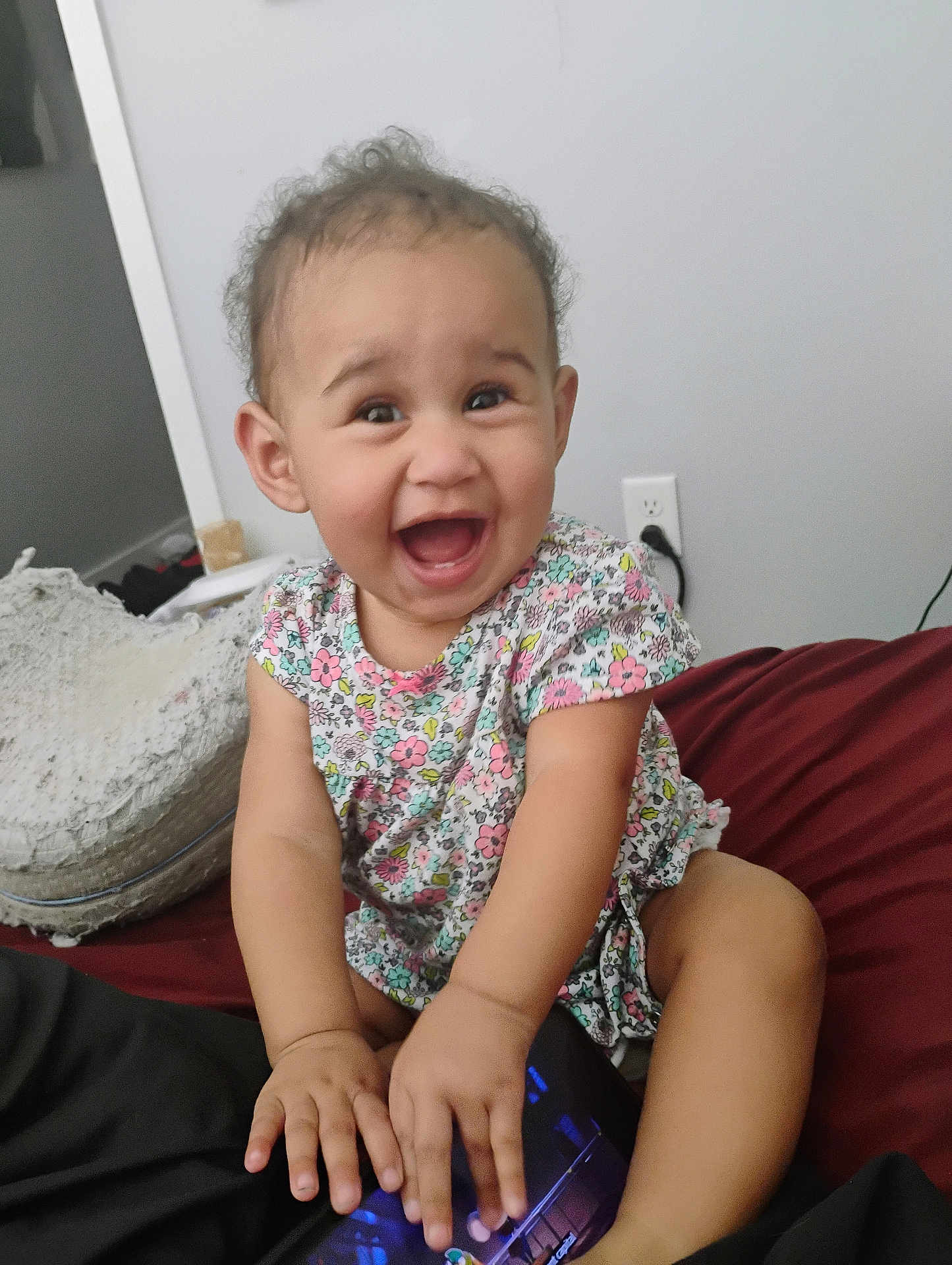 Kehlani joined the competition — help win amazing prizes! baby, child, smiling, happy, curly_hair, floral_dress, tablet, indoor, bed, sitting, hands, face, joyful, cute, person, room, sneaker, power_outlet, casual, home
