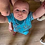 baby, child, infant, blue_shirt, dinosaur_print, wooden_floor, person, legs, dog, husky, pet, indoor, curious, looking_up, reaching, human, foot, animal, companion, cute