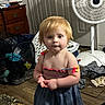 Isabelle is registered to the contest to win money with this photo: bare_shoulders, casual, child, clothing, clutter, curious, door, dress, expression, fan, floor, home, indoor, messy_room, person, red_hair, standing, toddler, wooden_dresser, young_child