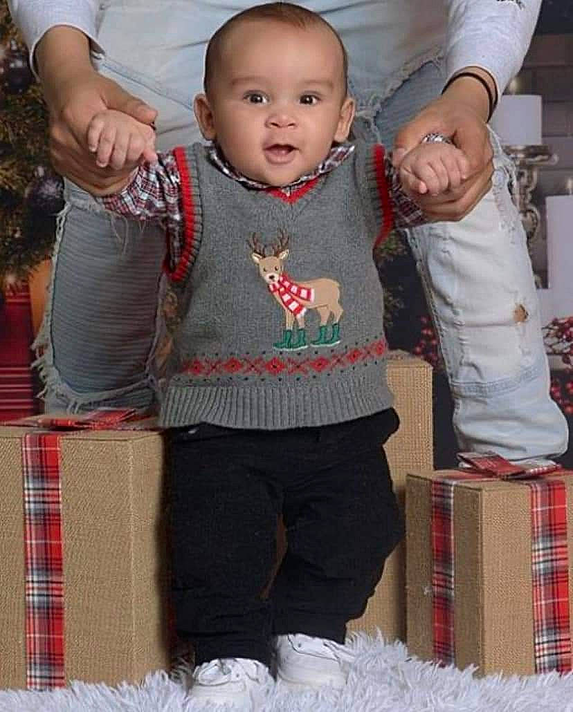 Javion is registered to the contest to win money with this photo: baby, baby_toddler_clothing, child, christmas_ornament, event, fun, gesture, happy, holiday, pattern, people, person, plaid, sitting, sleeve, sock, t_shirt, tartan, textile, toddler