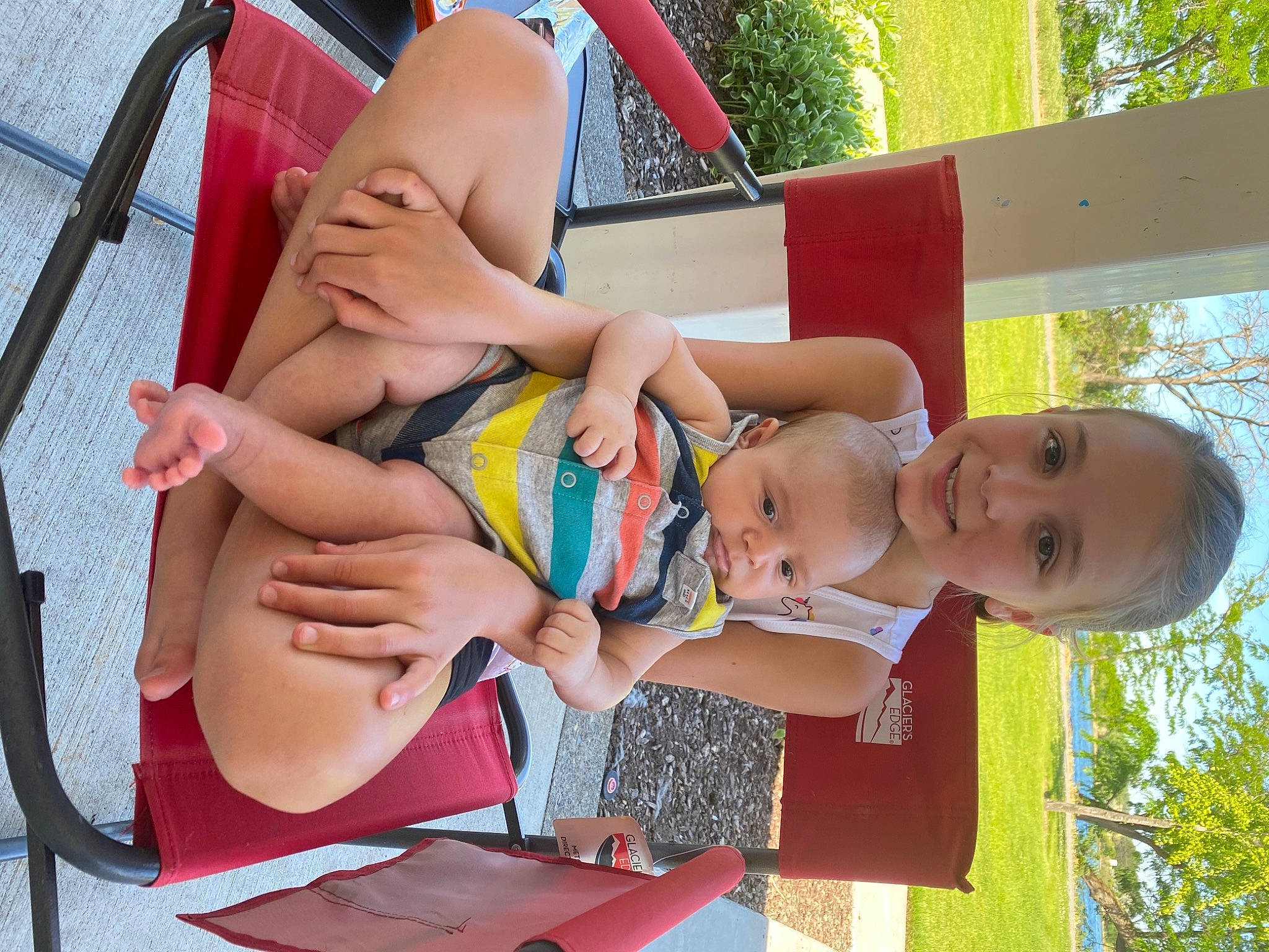 Everest is registered to the contest to win money with this photo: finger, fun, grass, happy, human_leg, joy, lap, leg, leisure, people_in_nature, person, plant, public_space, recreation, shorts, summer, thigh, tire, toddler, tree