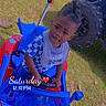 toddler, child, toy_car, outdoor, grass, blue, red, person, vehicle, offroad_vehicle, footwear, hairstyle, playtime, curious_expression, sunlight, daytime, casual_clothing, sitting, hand_on_steering_wheel, timestamp