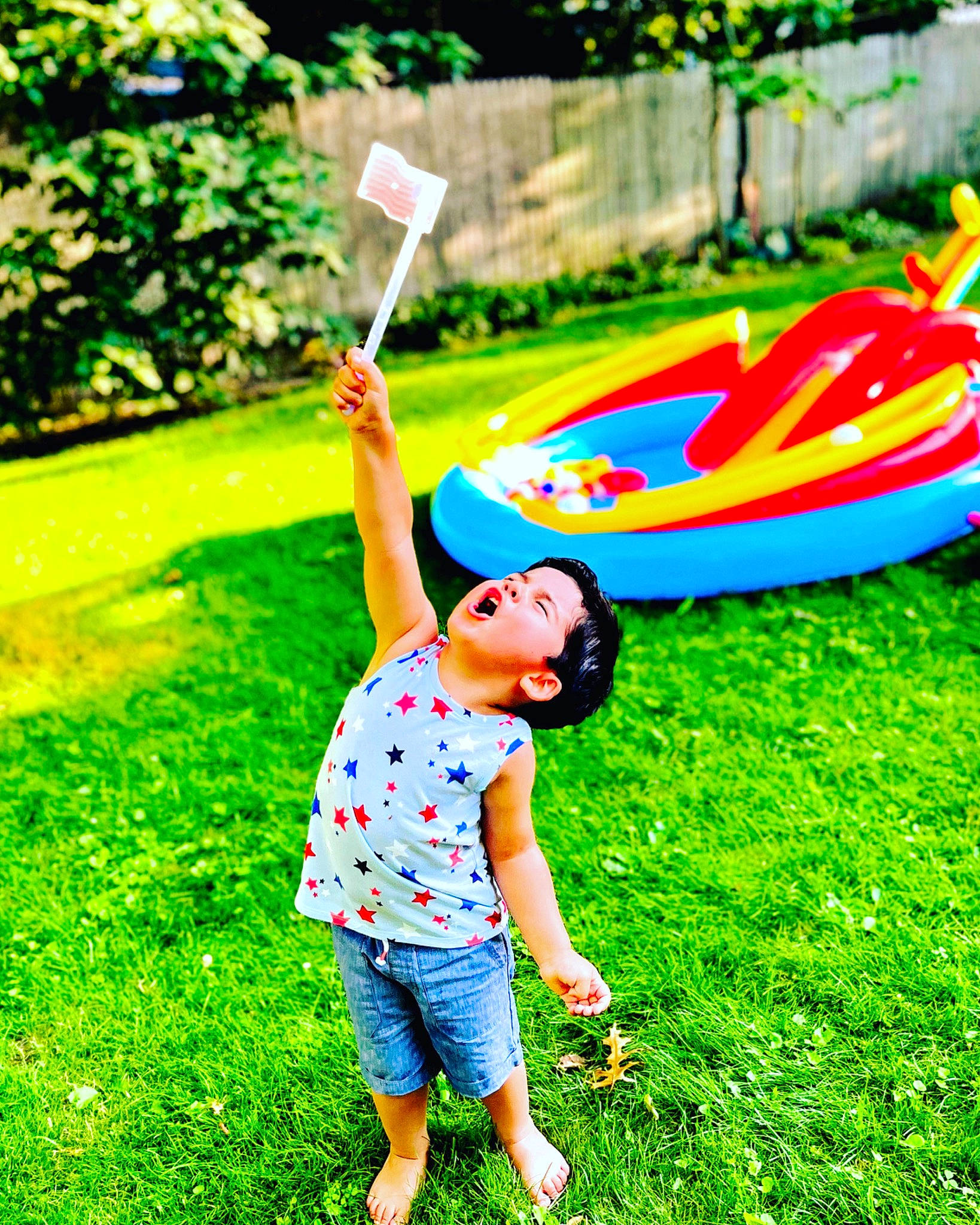 Landon is registered to the contest to win money with this photo: automotive_wheel_system, fun, grass, grass_family, grassland, green, happy, lawn, leisure, meadow, natural_environment, outdoor_recreation, people_in_nature, person, plant, recreation, shorts, sunglasses, t_shirt, toddler