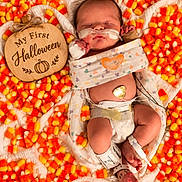 Wyatt is registered to the contest to win money with this photo: newborn, baby, infant, sleeping, halloween, candy_corn, hospital, medical_tubes, monitoring, pacifier, swaddle, blanket, wooden_sign, pumpkin, portrait, top_down, festive, indoor, face, parenting